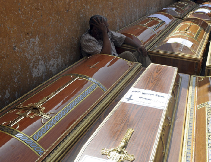 Credit : An Egyptian relative of one of the Coptic Christians killed during clashes with the Egyptian army late Sunday, mourns over coffin outside the morgue of the Copts hospital in Cairo. Thousands of mourners attend a funeral ceremony for those killed in overni