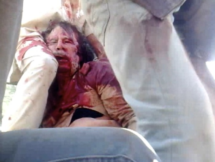 Former Libyan leader Muammar Gaddafi, covered in blood, is held on a truck by NTC fighters in Sirte in this still image taken from video footage Oct. 20, 2011.
