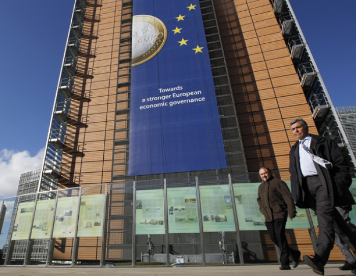 A banner featuring a Euro coin is seen on the European Commission headquarters building ahead of a European Union heads of state summit in Brussels October 26, 2011. German Chancellor Angela Merkel said Wednesday European leaders should agree on what would amount to a 50 percent writedown of the Greek debt held by the private sector.