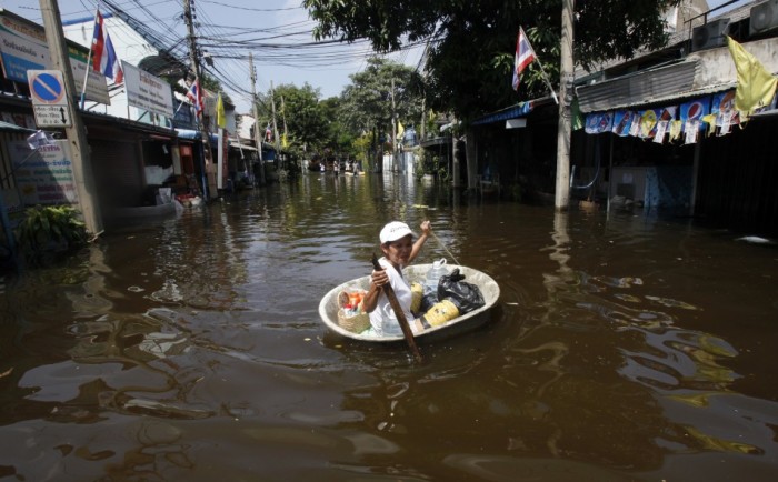 A woman paddles a basin with her belongings as she moves through a flooded area at Thung Song Hong district in Bangkok.