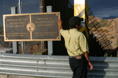 An illegal immigrant leans on a plaque marking the U.S. boundary with Mexico at Las Margaritas border crossing in Nogales, in the Mexican state of Sonora, July 26, 2010.