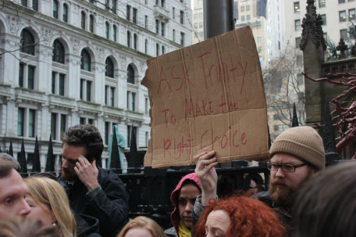 An Occupy protestor holding a sign asking for the Trinity Church to do 'the right thing' and allow them to stay on the property.