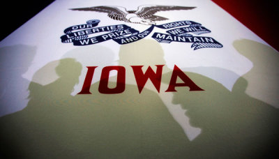 Potential caucus voters cast shadows on an Iowa state flag at a campaign rally for Republican presidential candidate Mitt Romney in Clive, Iowa January 2, 2012.