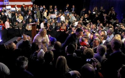 Republican presidential candidate and former Massachusetts Governor Mitt Romney (R) greets supporters at his New Hampshire primary night rally in Manchester, New Hampshire January 10, 2012. Romney's wife Ann (left center) also greets supporters.