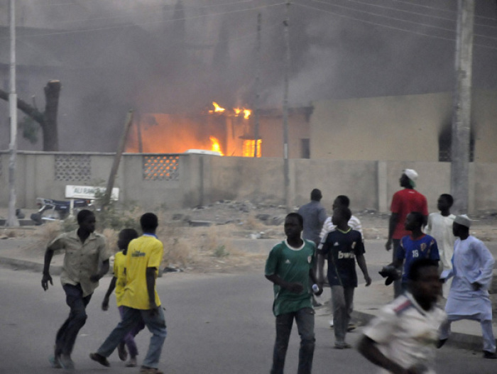 Smoke rises from the police headquarters as people run for safety in Nigeria's northern city of Kano January 20, 2012. Authorities imposed a curfew across the city, which has been plagued by an insurgency led by the Islamist sect Boko Haram.
