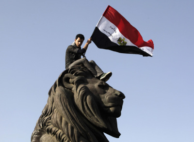 A demonstrator carries an Egyptian flag near Tahrir square as demonstrators gather to mark the first anniversary of Egypt's uprising, January 25, 2012.