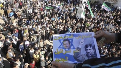 Demonstrators take part in a protest against Syria's President Bashar al-Assad after Friday prayers in Talbiseh, near Homs February 3, 2012. Poster show Syria's Assad (L) and Iranian President Mahmoud Ahmadinejad.