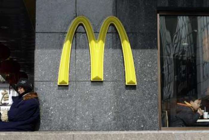 A child eats a hamburger at a McDonald's outlet in Beijing February 5, 2009. McDonald's Corp, the world's largest fast-food chain, has cut some prices by as much as a third in China where once booming economic growth has slumped amid the global financial crisis.