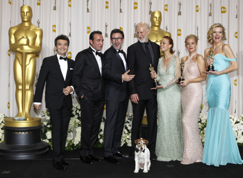 (L-R) Producer Thomas Langmann, Jean Dujardin, director Michel Hazanavicius, James Cromwell, Berenice Bejo, Penelope Ann Miller, Missy Pyle and the dog Uggie after winning best picture for "The Artist" backstage at the 84th Academy Awards in Hollywood, California, February 26, 2012.