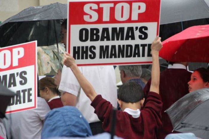 Protesters against President Obama's HHS mandate requiring religious institutions provide contraception and abortion related services through health insurance hold signs outside City Hall in Cincinnati, Ohio, March 23, 2012.