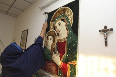 An Iraqi Christian refugee woman adjusts a carpet depicting Virgin Mary and Jesus at her house in Arbil, about 300 km (190 miles) north of Baghdad, September 11, 2011.