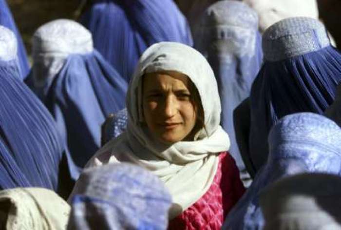 A young Afghan woman shows her face in public for the first time after 5 years of Taliban Sharia law as she waits at a food distribution centre in central Kabul November 14, 2001. Under its strict interpretation of Islam, the Taliban ordered all women hidden behind head-to-toe burqas.