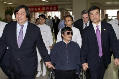 A handout photo from the U.S. Embassy Beijing Press office shows blind activist Chen Guangcheng (C) sitting in a wheelchair as he is accompanied by U.S. Ambassador to China Gary Locke (R) at a hospital in Beijing, May 2, 2012. Picture taken May 2, 2012.