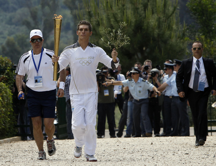 Spyridon Gianniotis, Greece's world champion of swimming, runs with the Olympic flame and an olive branch during the Olympic torch relay at the site of ancient Olympia in Greece May 10, 2012.