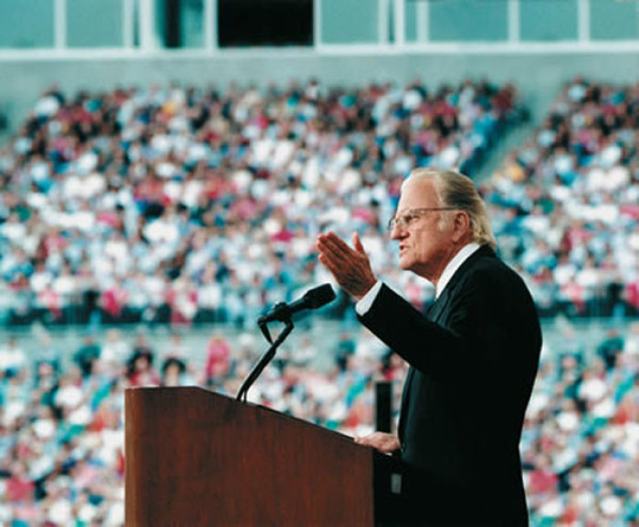 Evangelist Billy Graham preaches to thousands.
