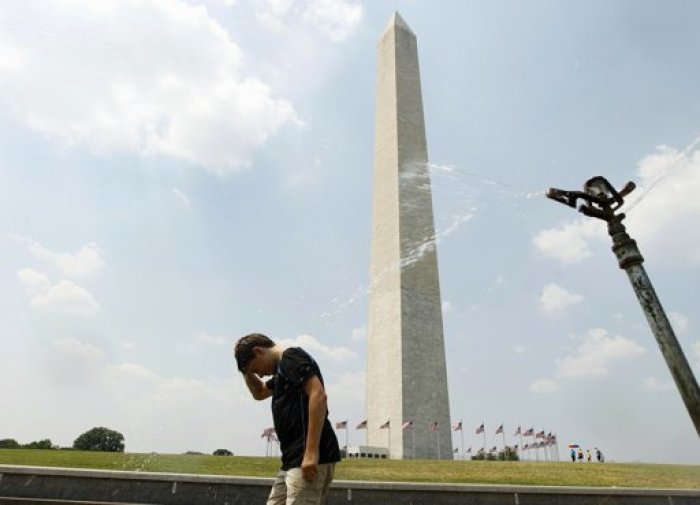 Timmy Doyle refreshes himself at a sprinkler as he passes by the Washington monument in Washington.