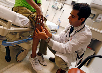 Patient Sharon Dawson Coates (L) has her knee examined by Dr. Nikhil Narang at University of Chicago Medicine Urgent Care Clinic in Chicago June 28, 2012.
