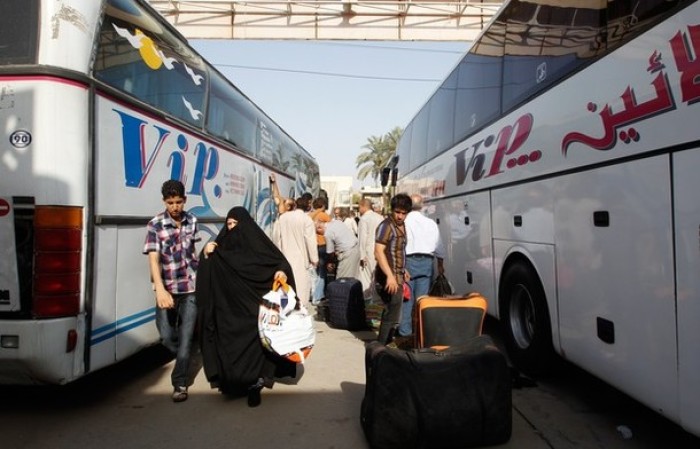 People unload their belongings from a bus that has traveled from Syria after arriving in Baghdad July 20, 2012. Iraq on Tuesday called on tens of thousands of its citizens still living in Syria to return home because of escalating violence in its neighbor, after police said two Iraqi journalists had been killed in Damascus.