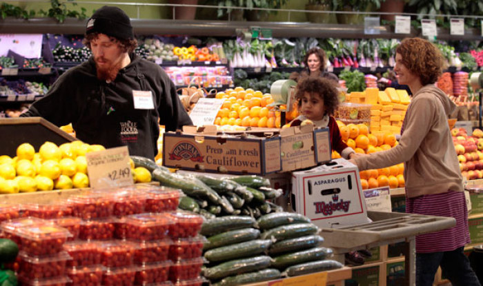 Whole Foods grocery store worker Adam Pacheco (L) stacks vegetables while customers shop in the produce section at the Whole Foods grocery story in Ann Arbor, Michigan, March 8, 2012.
