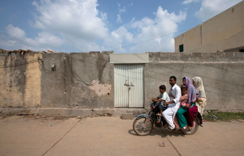 A family rides past the locked house of Rimsha Masih, a Pakistani Christian girl accused of blasphemy, on the outskirts of Islamabad on August 23, 2012.