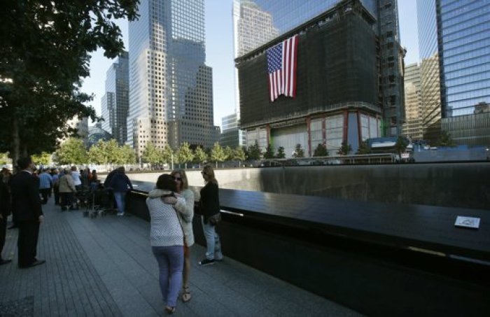 Two women embrace at the edge of the North Pool of the 9/11 Memorial during ceremonies marking the 11th anniversary of the attack on the World Trade Center in New York, September 11, 2012. One World Trade Center is at back.