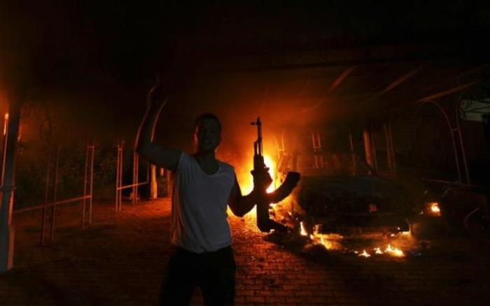 A protester reacts as the U.S. Consulate in Benghazi is seen in flames during a protest by an armed group said to have been protesting a film being produced in the United States Sept. 11, 2012. The U.S. ambassador to Libya and three other embassy staff were killed in a rocket attack on their car, a Libyan official said, as they were rushed from a consular building stormed by militants denouncing a U.S.-made film deemed insulting to the Prophet Mohammad.