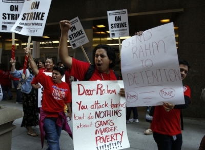 Chicago teachers hold placards as they walk the picket line outside the headquarters of Chicago Public Schools in Chicago September 10, 2012. Thousands of public school teachers formed picket lines in Chicago on Monday and parents scrambled for child care during their first strike in a quarter century over reforms sought by Mayor Rahm Emanuel and endorsed by President Barack Obama's administration.