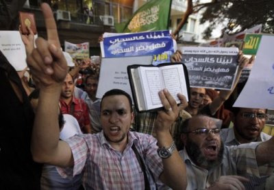 People shout and hold slogans in front of the U.S. embassy during a protest in Cairo September 11, 2012. Egyptian protesters scaled the walls of the U.S. embassy on Tuesday, tore down the American flag and burned it during a protest over what they said was a film being produced in the United States that insulted Prophet Mohammad.