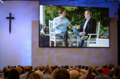 Reality TV pioneer Mark Burnett (L) is interviewed by Pastor Rick Warren during a videotaped segment shown at a economic business summit at Saddleback Church, Oct. 19, 2012.