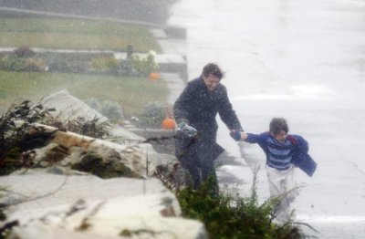 A woman holds the hand of her child as they run from their house to their car before the arrival of Hurricane Sandy in Scituate, Massachusetts October 29, 2012. Hurricane Sandy began battering the U.S. East Coast on Monday with fierce winds and driving rain, as the monster storm shut down transportation, shuttered businesses and sent thousands scrambling for higher ground hours before the worst was due to strike.