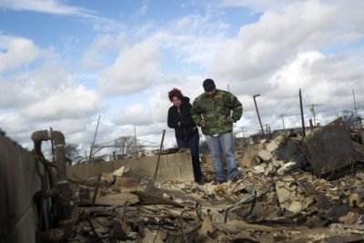 A man, who asked not to be identified, stands with Lucille Dwyer on among the wreckage of their homes devastated by fire and the effects of Hurricane Sandy in the Breezy Point section of the Queens borough of New York October 31, 2012. The U.S. Northeast began crawling back to normal on Wednesday after monster storm Sandy crippled transportation, knocked out power for millions and killed at least 45 people in nine states with a massive storm surge and rain that caused epic flooding.