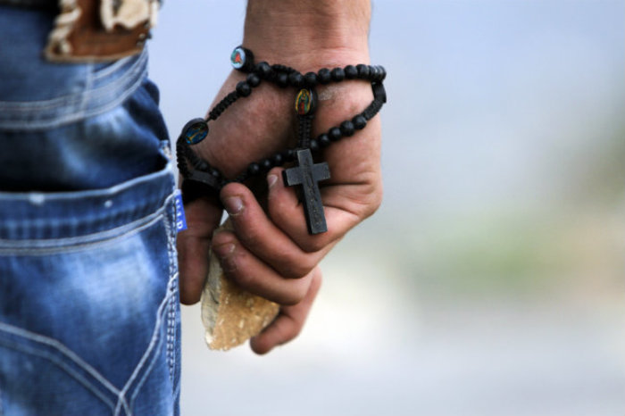 A Palestinian demonstrator wearing a rosary holds a stone during minor clashes with Israeli troops in protest against Israel's military operation in the Gaza Strip, in the West Bank village of Bir Zeit, near Ramallah on Nov. 19, 2012.