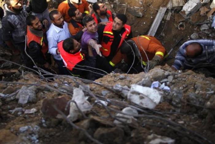 Palestinian members of the Civil Defense help a survivor after he was pulled out from under the rubble of his destroyed house after an Israeli air strike in Gaza City on Nov. 18, 2012.