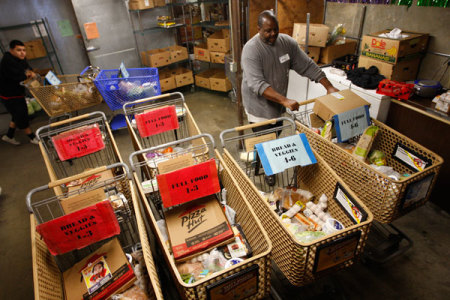 Workers fill carts with food for the poor at the Foothill Unity Center food bank in Monrovia, California, November 14, 2012. The number of people served by the Foothill Unity Center has tripled in the last four years. Groups that provide food for pantries say this is one of the toughest years yet in terms of low levels of federal government "surplus" commodity donations, which have accounted for a major portion of meat and other proteins in the past. Those shortfalls are putting real pressure on low income families and individuals, who are more squeezed than ever because of still high unemployment, federal and state budget cuts, higher grocery costs from recent drought, rising rents and transport costs.
