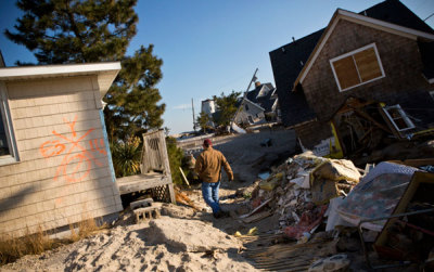 A man walks among the debris of homes destroyed by Hurricane Sandy, one month after the storm made landfall, in Mantoloking, New Jersey, November 29, 2012.