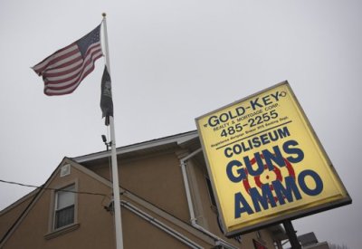The American flag is seen flying next to the Coliseum Gun Traders Ltd. sign in Uniondale, New York January 16, 2013. President Barack Obama proposed a new assault weapons ban and mandatory background checks for all gun buyers on Wednesday as he tried to channel national outrage over the Newtown school massacre into the biggest U.S. gun-control push in decades.