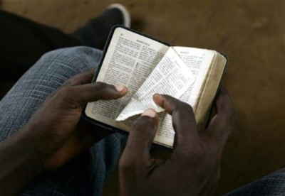 A boy turns a page of a Bible during a mass at the Simulambuco church in Cabinda, Angola, on Jan. 17, 2010. (FILE)