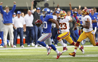 New York Giants Victor Cruz (L) runs for the game winning touchdown next to Washington Redskins Madieu Willims (R) and DeAngelo Hall (C) in the fourth quarter during their NFL football game in East Rutherford, New Jersey, October 21, 2012.