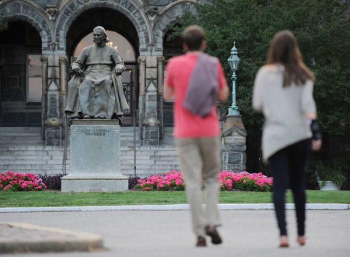 Two women walk past a statue of John Carroll, first Archbishop of Baltimore and founder of Georgetown University, on the campus in Washington June 14, 2012. Controversy lingers at some Catholic institutions struggling to balance the rules requiring free access to prescription birth control for women with health insurance with their opposition to contraception.
