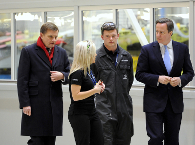 Britain's Prime Minister David Cameron (R) and Secretary of State for Wales David Jones (L) speak to apprentices Fleur O'Hagan and Philip Broodbank during a visit to Airbus UK in Broughton, north Wales December 13, 2012.