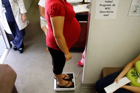 A pregnant woman stands on a scale before receiving a prenatal exam at the Maternity Outreach Mobile in Phoenix, Arizona.