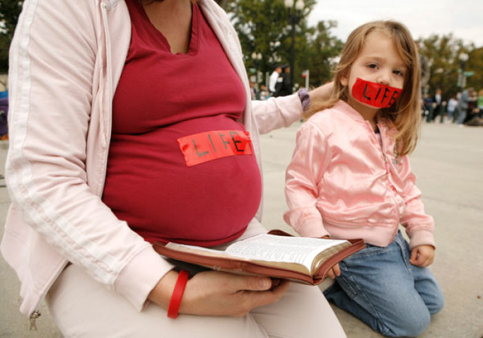 A pregnant pro-life demonstrator and her daughter kneel before the Supreme Court in Washington October 6, 2008. Amid a presidential race that may decide its future direction, the Supreme Court began a new term today with cases about tobacco company lawsuits, protecting whales from Navy sonar and a government crackdown on dirty words on television.
