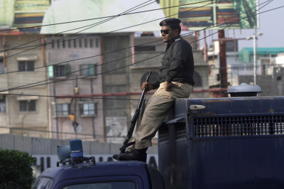 A police officer sits on the top part of a prison van while watching over a road in Pakistan in this file photo.