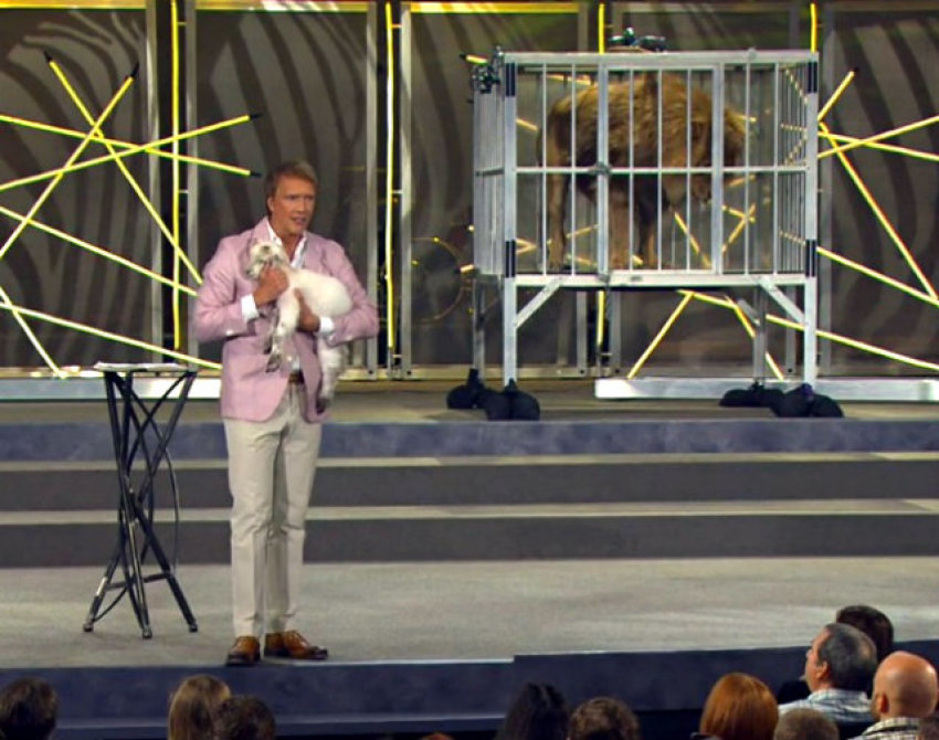 Pastor Ed Young of Fellowship Church in Grapevine, Texas, holds a lamb near a cage with a live lion during his Easter "Wild" sermon on April 8, 2012.