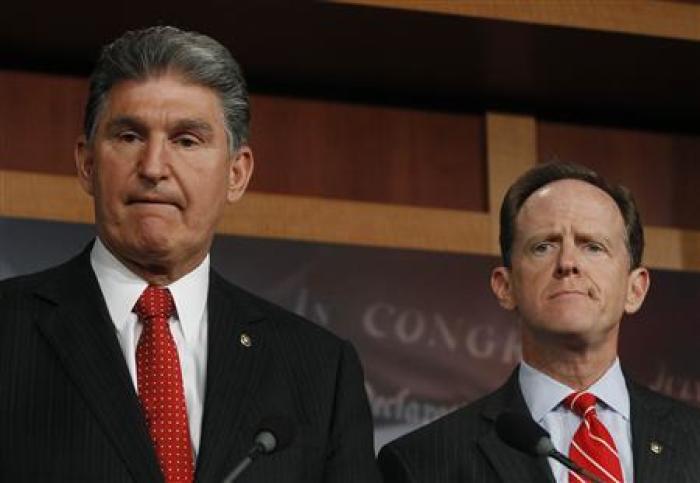 Senator Pat Toomey (R-PA) (R) and Senator Joe Manchin (D-W.VA) (L) hold a news conference on background checks for firearms on Capitol Hill in Washington April 10, 2013.