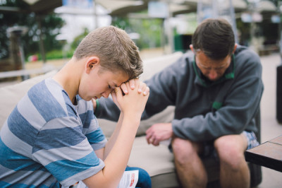 A father prays with his son during a breakout session of the IGNITE men's conference at Saddleback Church in Lake Forest, Calif., on Saturday, April 13, 2013.