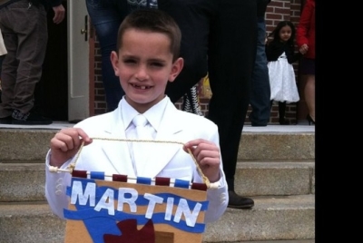 Martin Richard, the 8-year-old Boston Marathon bombing victim, can be seen here celebrating his first communion holding a banner with a dove on it symbolizing the Holy Spirit.