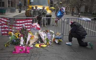 A man kneels praying in front of a make shift memorial on Boylston Street a day after two explosions hit the Boston Marathon in Boston, Massachusetts April 16, 2013.