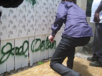 Joel Osteen uses dark green spray paint to sign his name on the newly painted white fence at Curley's Garden in downtown Miami, Fla., on April 18, 2013.