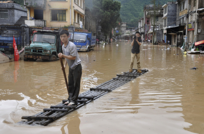 A journalist (R) records a video on a raft as a man paddles along flooded street after heavy downpours hit Jianghua Yao Autonomous County, Hunan province May 16, 2013. One person died and 270,000 others were affected by a new round of rain in central China's Hunan Province, authorities said.